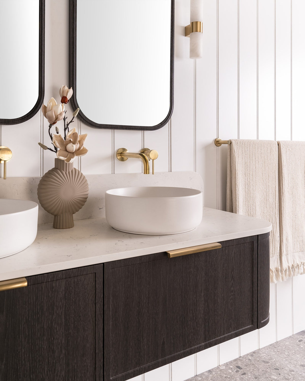 Flo Wall Hung Vanity - Flo 1500 Double Bowl, Estella Oak, Mont Blanc Cherry Pie benchtop. Brushed Brass Francis Handles. Quinn Mirrored Cabinets, Estella Oak. Margot Above Counter basins, Matte White. Bloom Tapware, Light Brushed Brass